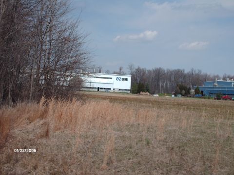 1995 Ford Probe - A wide shot captures industrial buildings under a cloudy sky, with a field in the foreground and a date stamp.
