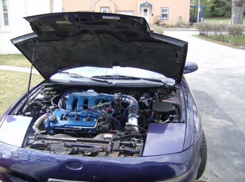 1996 Ford Probe - Engine bay of a purple coupe, hood up, showing a transverse engine with a blue valve cover and aftermarket cold-air intake tubing.