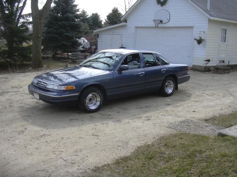 1996 Ford Crown Victoria - A dark blue 1995 Ford Crown Victoria is parked in front of a white garage.