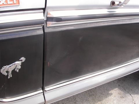 1979 Ford Bronco - A chrome running horse emblem is visible on the side of a two-tone vehicle door.