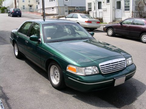 2001 Ford Crown Victoria - Green 2001 Ford Crown Victoria sedan parked on a residential street with other vehicles visible.