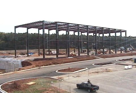 1988 Ford Bronco - A large steel structure is being erected on a construction site, with a pickup truck visible in the parking area.