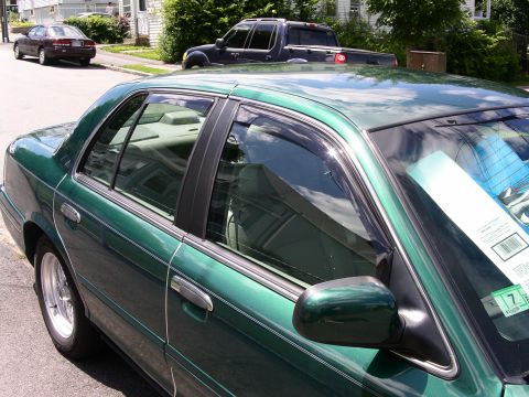 2001 Ford Crown Victoria - Side view of a green 2001 Ford Crown Victoria parked on a residential street with other vehicles present.