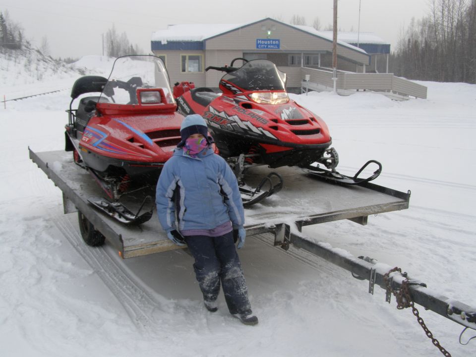 Two snowmobiles on a trailer in front of Houston City Hall