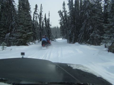 2000 Ford E350 - Two snowmobiles are seen from the perspective of a vehicle driving behind them on a snowy forest trail.