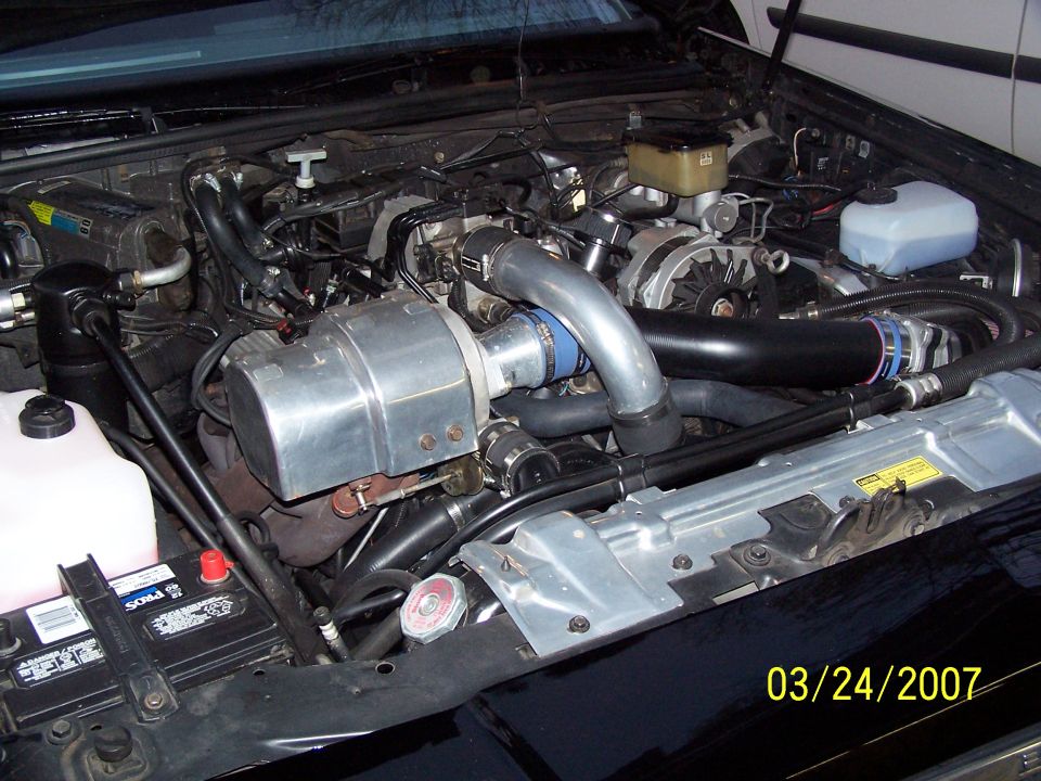 Engine bay with a large turbocharger and intercooler piping. Battery is visible on the left