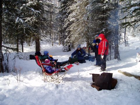 2000 Ford E350 - A group of people enjoy a winter gathering around a campfire in a snowy forest.