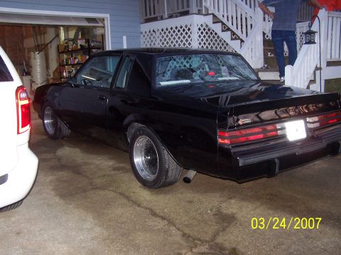 1979 Ford F-150 - A black coupe with aftermarket wheels is parked in a garage, with a white vehicle partially visible on the left.