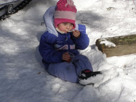 2000 Ford E350 - A child sits in the snow, bundled in winter clothing and eating with a spoon.