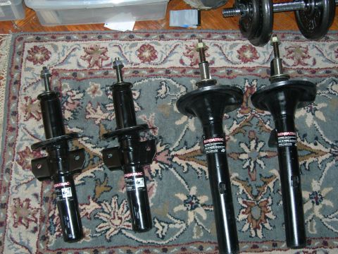 1992 Ford Taurus - Four SensaTrac shock absorbers are displayed on a patterned rug, with dumbbells in the background.
