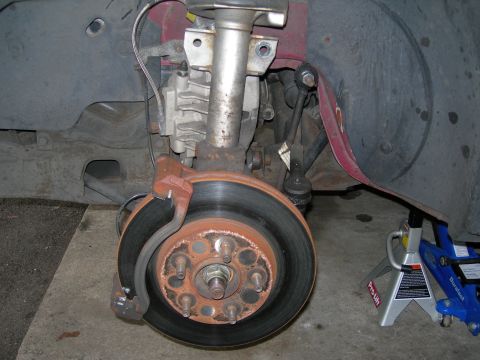 1992 Ford Taurus - Close-up of a vehicle's front suspension and brake system, showing worn components and repair equipment.