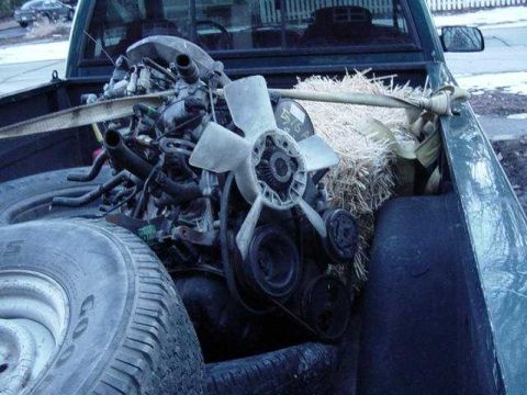 1992 Ford Bronco - Engine and fan assembly loaded in the bed of a pickup truck with straw for padding.