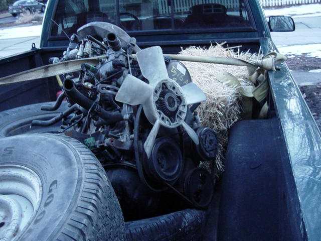 Engine and fan assembly with straw and strap in a truck bed next to a tire