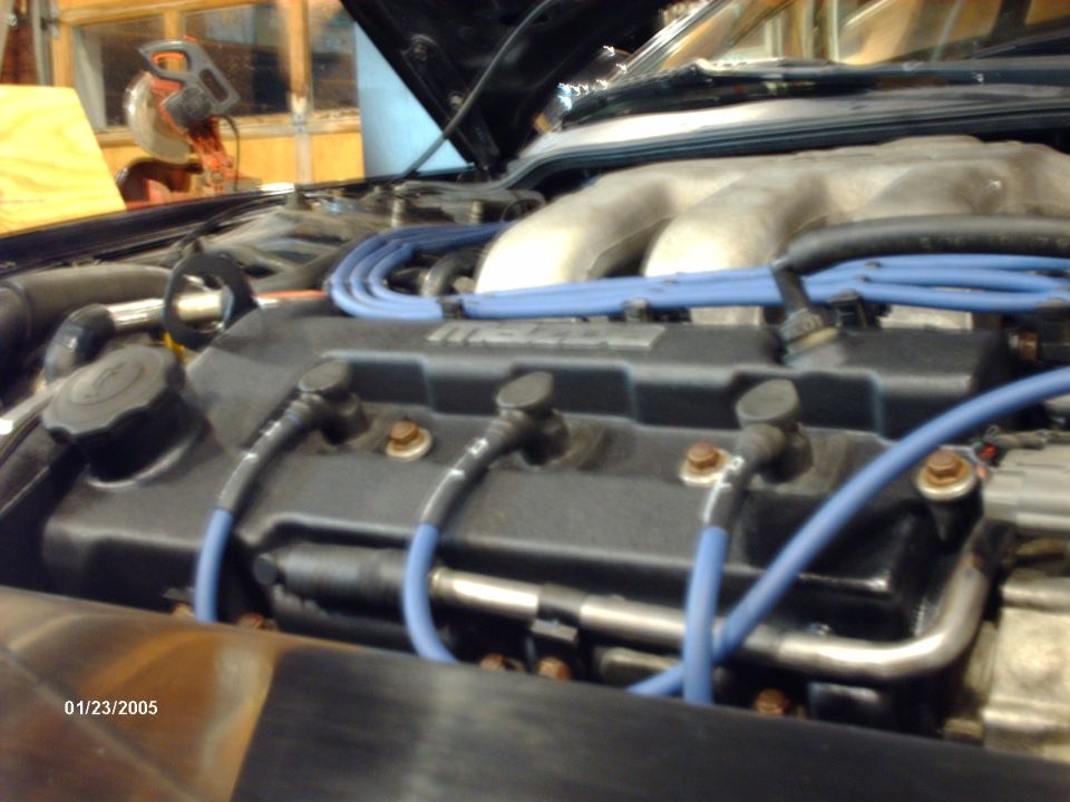 Engine bay with blue spark plug wires and a silver intake manifold. Date stamp 01/23/2005