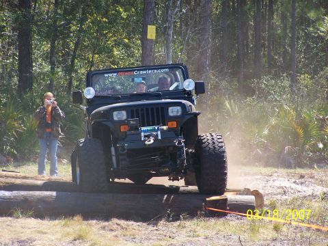 1989 Ford Bronco - Jeep Wrangler navigates an off-road obstacle course on logs.