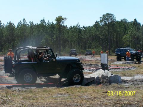 1989 Ford Bronco - Off-road vehicles navigate a rocky obstacle course on a sunny day.