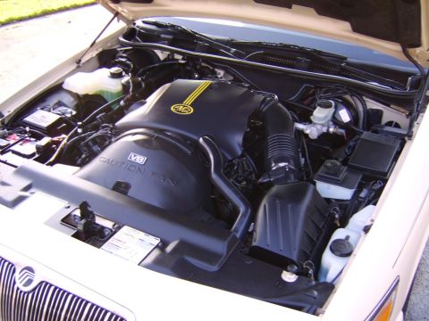 1996 Mercury Grand Marquis - Engine bay of a 1996 Mercury Grand Marquis, a V8 engine and distinctive yellow stripes on the cover.
