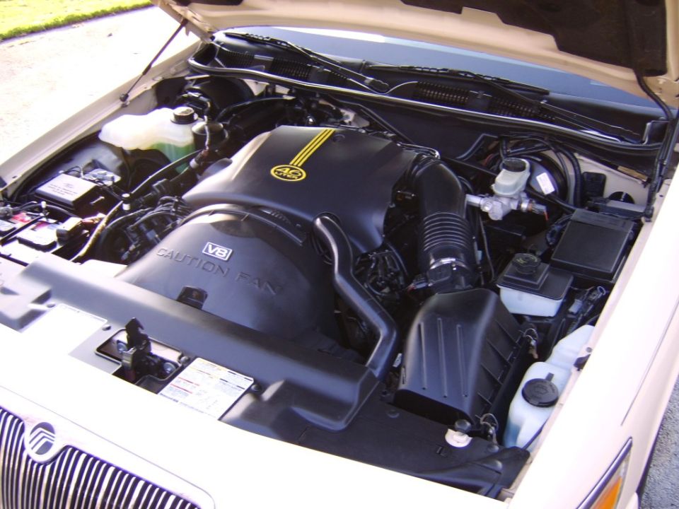 White Mercury sedan engine bay with black 4.6 V8 cover and air intake