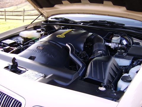 1996 Mercury Grand Marquis - The engine bay of a car, a V8 engine cover with yellow stripes and caution fan warning.