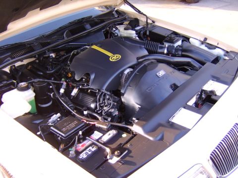 1996 Mercury Grand Marquis - The engine bay of a 1996 Mercury Grand Marquis, its V8 engine and distinctive yellow stripe badging on the cover.