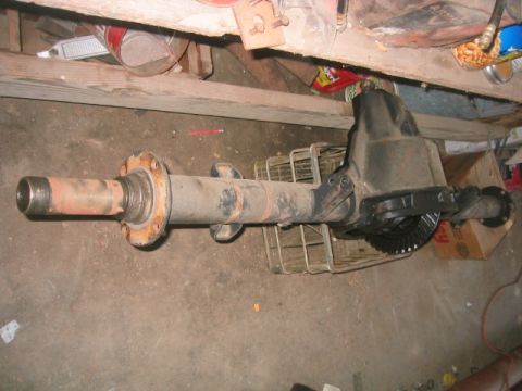 1973 Ford F-100 - A bare heavy-duty axle housing lying on a garage floor with its differential cover removed, exposing the ring gear and carrier; the long tu…