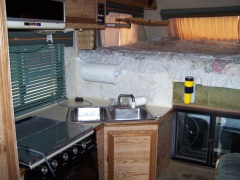 1989 Ford F-250 - The interior of a recreational vehicle features a sleeping area above the kitchen and driving cabin.
