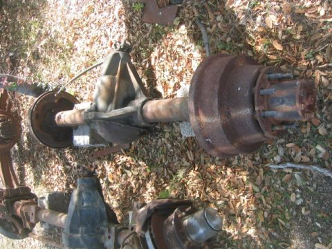 1973 Ford F-100 - Two rusty rear axle assemblies are shown lying on the ground amongst fallen leaves.