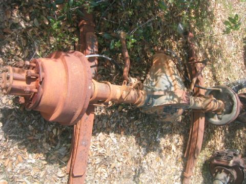 1973 Ford F-100 - This heavily rusted rear axle assembly, likely from a truck, is shown lying on the ground.