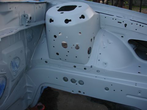 1992 Ford Taurus - The engine bay of a vehicle, coated in primer, reveals its internal structure and various openings.