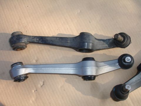 1992 Ford Taurus - Comparison of a used black control arm and a new silver control arm, both automotive suspension parts.