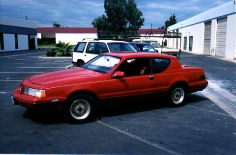 1993 Ford Bronco - A red coupe is parked in a lot with a white SUV visible in the background.