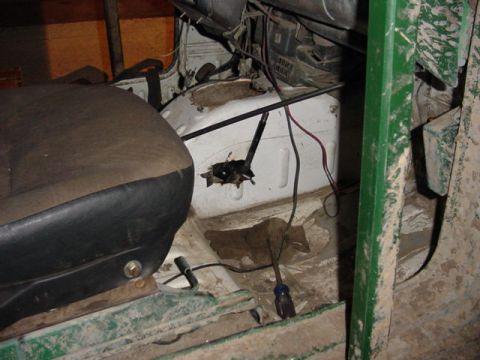1992 Ford Bronco - Interior view of a vehicle with a worn seat and exposed wiring against a white firewall and green frame.