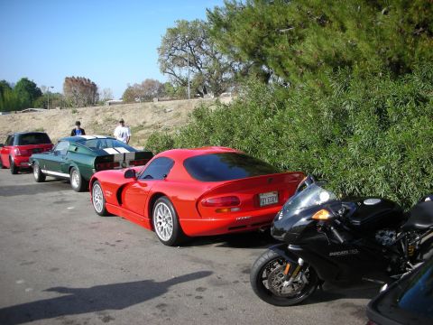 1998 Ford Crown Victoria - red Dodge Viper coupe parked outdoors alongside a black Ducati sportbike and a green Shelby Mustang fastback.
