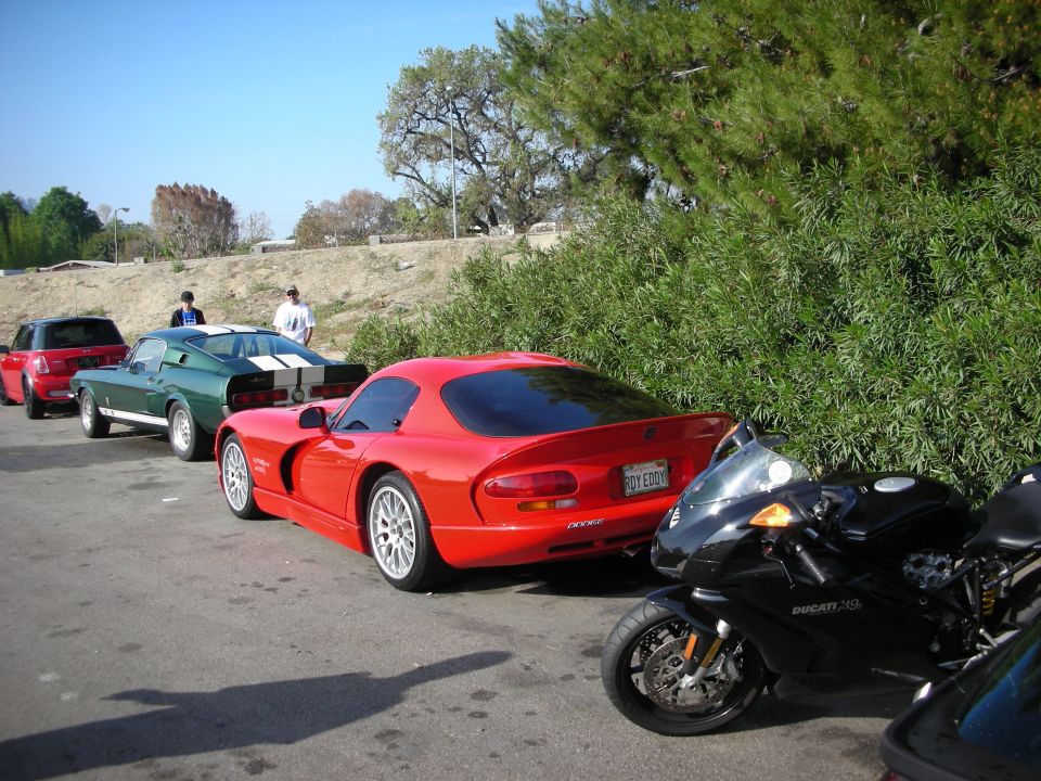 Red Dodge Viper coupe parked beside a Ducati motorcycle and a green Shelby Mustang