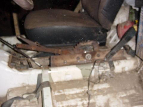 1992 Ford Bronco - The interior of the vehicle shows a close-up of the seat mounting hardware and the floor, which appears to be covered in dirt and debris.