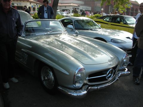 1998 Ford Crown Victoria - silver classic Mercedes-Benz 300SL with chrome grille and bumper parked among spectators at an outdoor car show.