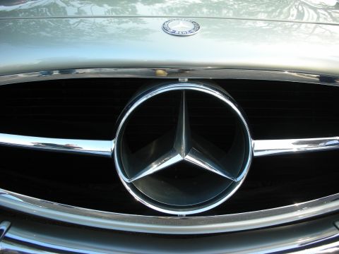 1998 Ford Crown Victoria - Extreme close-up of the chrome three-pointed star emblem set in the grille of a classic Mercedes-Benz.