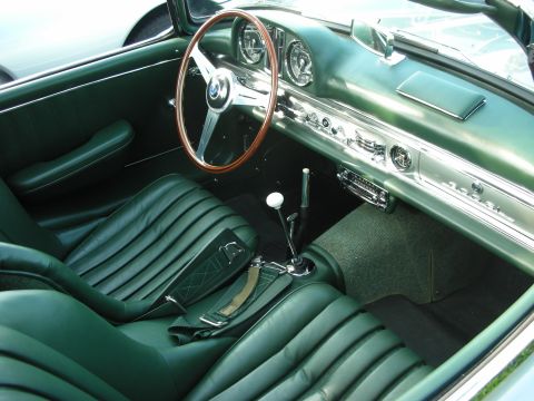1998 Ford Crown Victoria - Interior of a classic roadster featuring dark green pleated leather seats, a wood-rimmed steering wheel and a chrome floor shifter.
