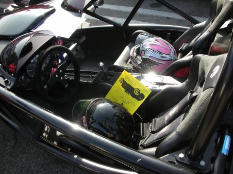 1998 Ford Crown Victoria - open cockpit of a tube-frame track car holds twin bucket seats, helmets, harnesses and a small detachable steering wheel.