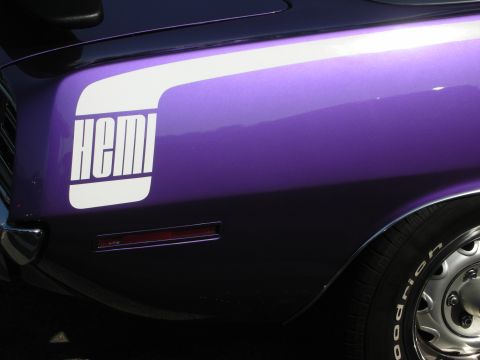 1998 Ford Crown Victoria - Close-up of a purple muscle car's rear quarter panel showing a bold white 'HEMI' graphic above the chrome bumper and wide tire.