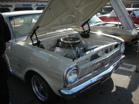 1998 Ford Crown Victoria - white vintage compact car displays its chromed V8 engine under an open hood at an outdoor car show.
