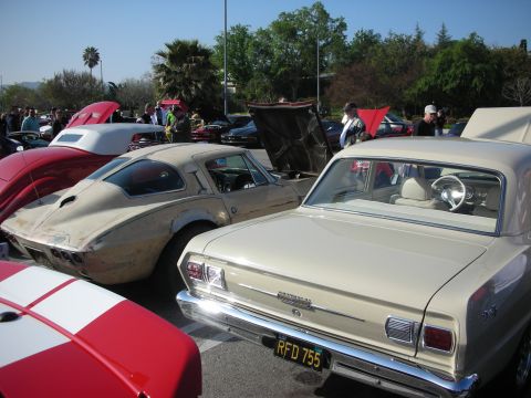 1998 Ford Crown Victoria - cream sedan with plate RFD 755 sits beside a faded fastback sports car among rows of cars at an outdoor show.