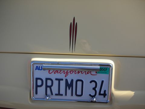 1998 Ford Crown Victoria - Rear of a cream car showing a California PRIMO 34 plate beneath a red triple-pinstripe accent, dated 2007.