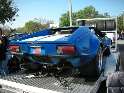 1998 Ford Crown Victoria - Rear three-quarter of a blue De Tomaso Pantera race car with US flag, twin exhausts and West Coast Racing Inc. lettering, on a trailer.