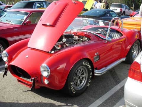 1998 Ford Crown Victoria - red Shelby Cobra roadster with its hood raised showing the engine, side pipes and Goodyear Eagle tires at a show.
