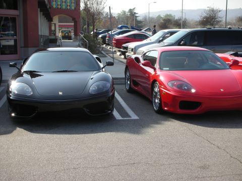 1998 Ford Crown Victoria - black Ferrari 360 and a red Ferrari 360 parked side by side in a lot, with more cars lined up behind them.