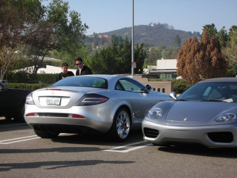 1998 Ford Crown Victoria - Rear three-quarter view of a silver Mercedes-Benz SLR McLaren parked next to a silver Ferrari with hills behind.