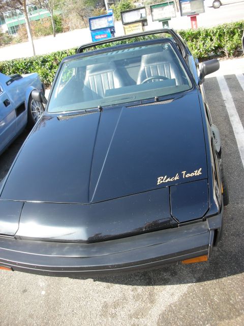 1998 Ford Crown Victoria - Overhead front view of a black 1980s coupe with grey interior and Black Tooth script lettering on the front fender.