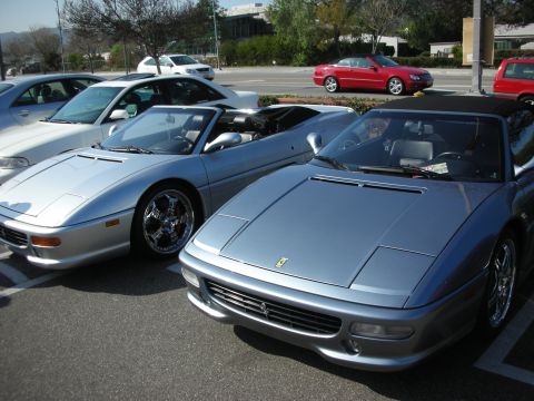 1998 Ford Crown Victoria - silver Ferrari F355 Spider parks next to a blue-grey Ferrari F355 convertible with a red coupe across the street.