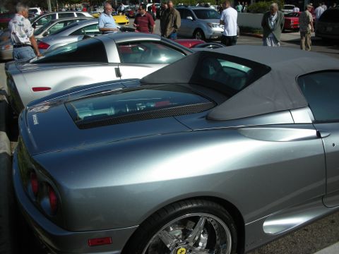 1998 Ford Crown Victoria - grey Ferrari 360 Spider with its soft top raised sits in a row of cars as spectators gather at a morning car meet.